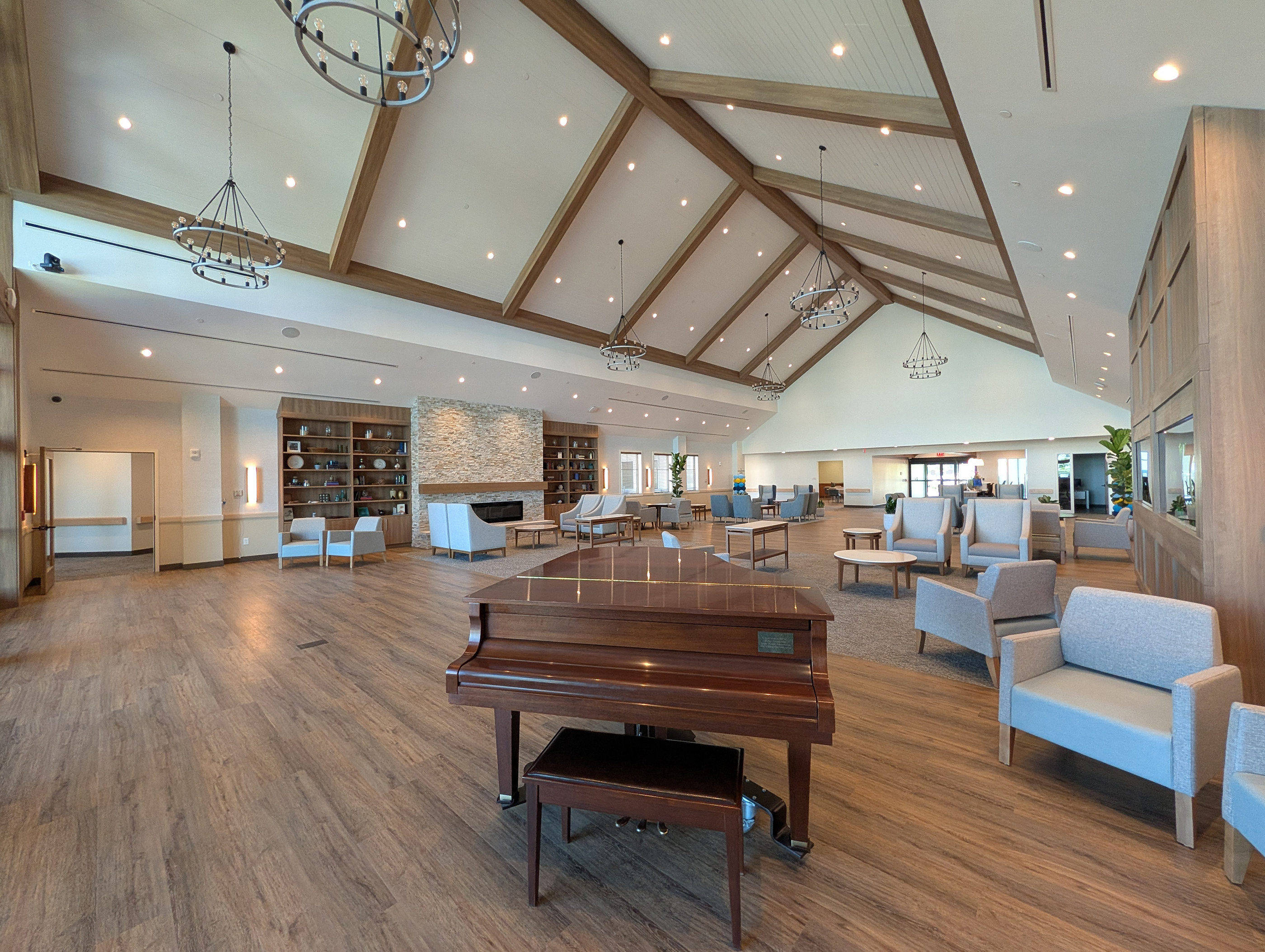 Spacious great hall with a high ceiling, natural chandeliers, wood floor and grand piano