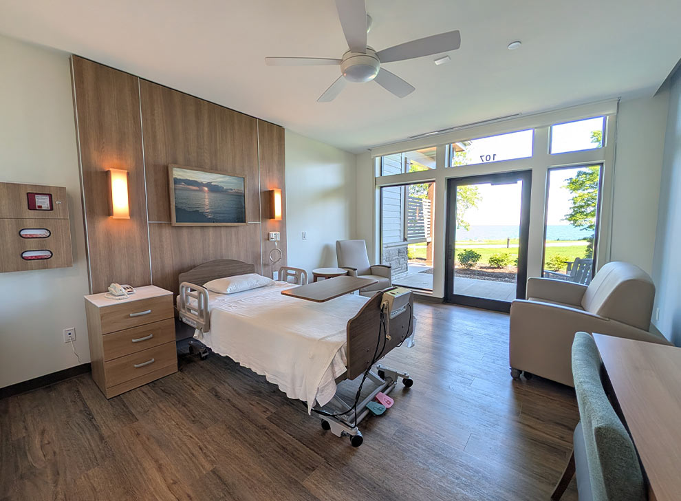 Private patient room featuring a hospital bed, comfortable seating, and large windows overlooking the water