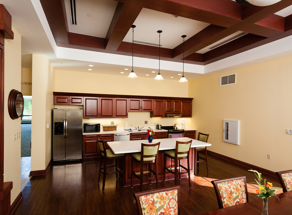 Kitchen and dining area with tables, chairs, and wood cabinetry.