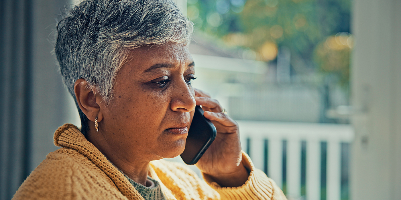 Person speaking on a phone while sitting indoors near a window