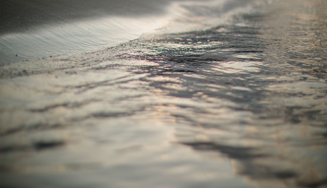 Abstract close-up of shallow water ripples with muted reflections