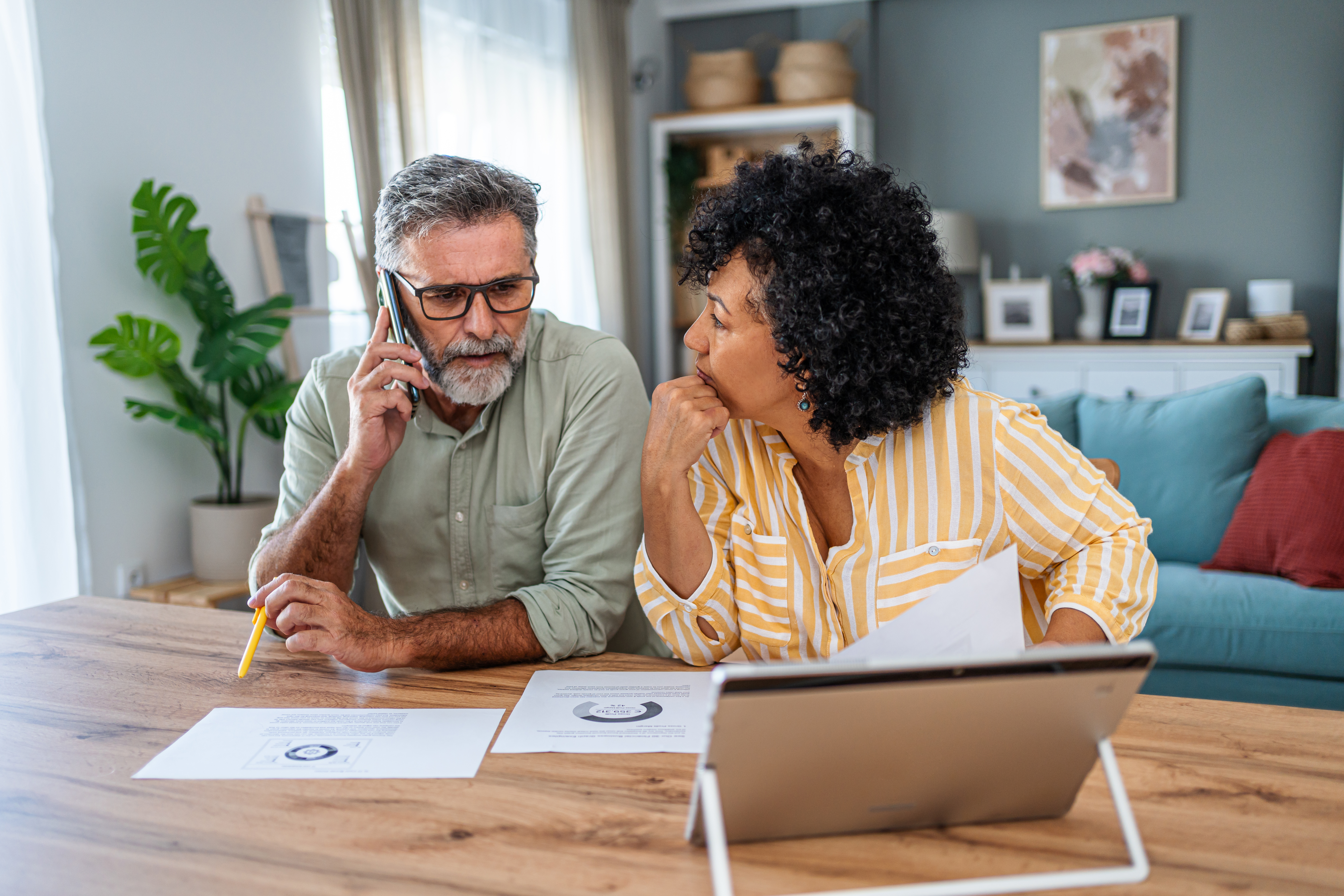 Couple reviewing paperwork together while speaking on the phone.