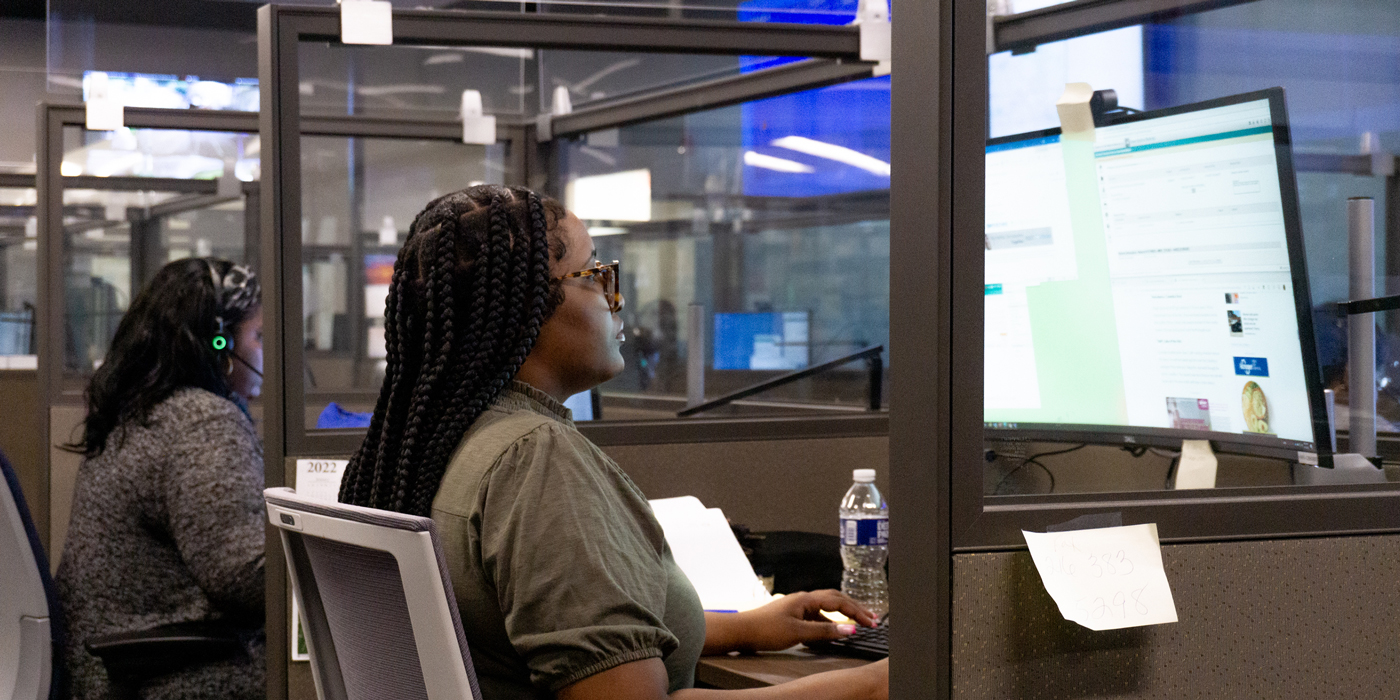 People working at computers inside an office with partitioned workstations