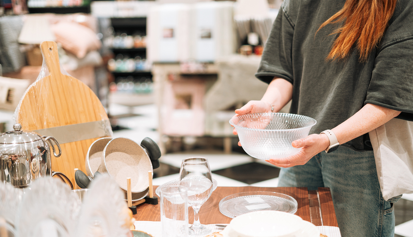 Person holding a glass bowl while shopping for home goods.