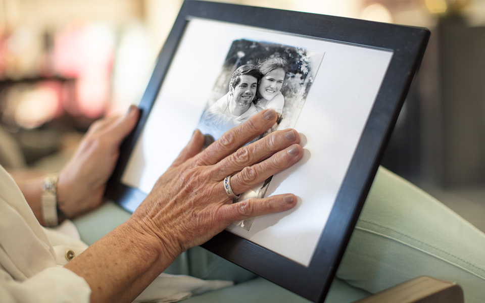 Person holding and touching a framed black-and-white photograph