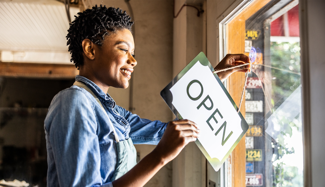 Person hanging an open sign on a door